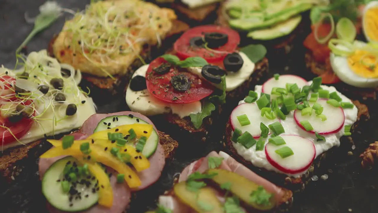 Variety of healthy fresh sandwiches with different vegetables herbs and ingredients on dark table