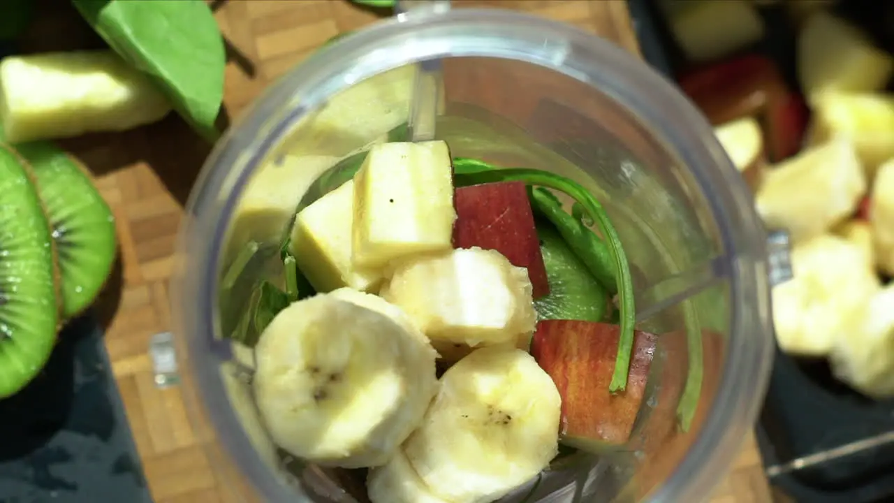 Close Up of Female Hands Placing Sliced Banana In Blender