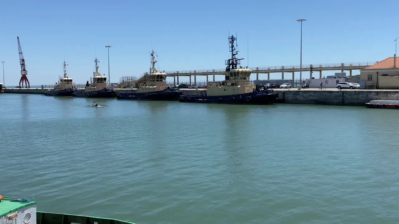 zoom in to some armed forces ships on the river with some sportsmen doing canoeing Alcântara Portugal