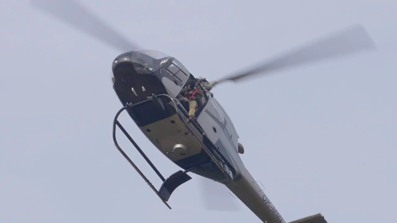 Military Helicopter With Soldier Holding Sniper Rifle Flying in the Sky Low Angle