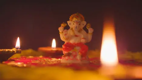 Statue Of Ganesh On Table Decorated With Diya Lamps For Celebrating Festival Of Diwali 2