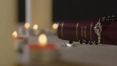 Tracking Shot of Candles Lit around Holy Bible and Crucifix