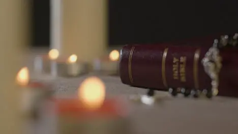 Tracking Shot of Candles Lit around a Holy Bible and Crucifix