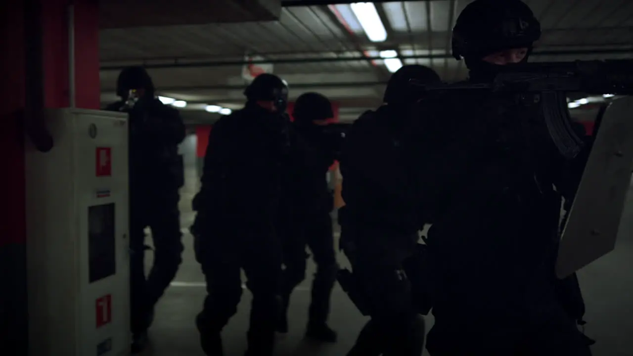 Group of SWAT members walking on underground parking with weapons