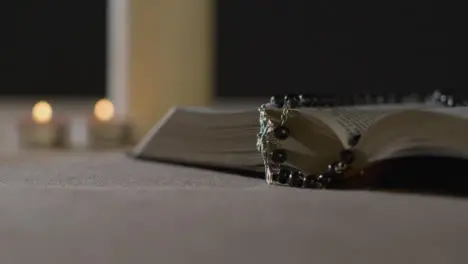 Tracking Shot of Candles Lit around Bible and Crucifix