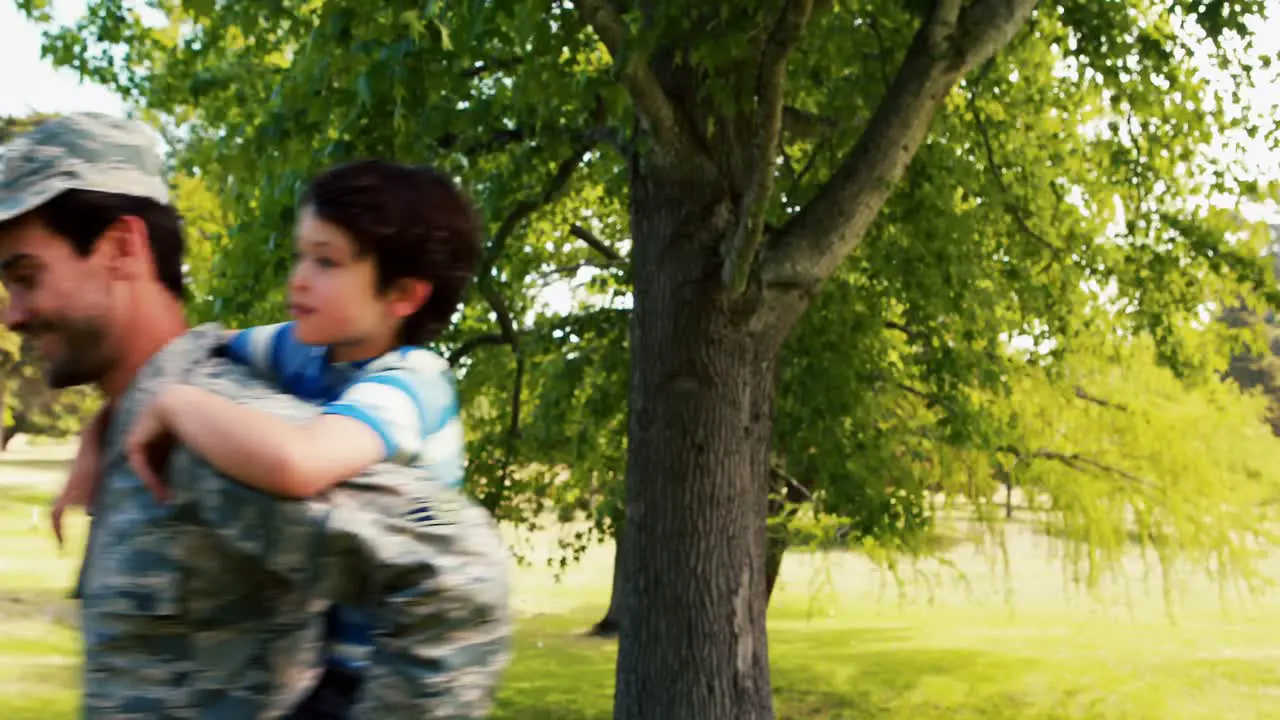 Smiling army soldier giving piggyback ride his son in park