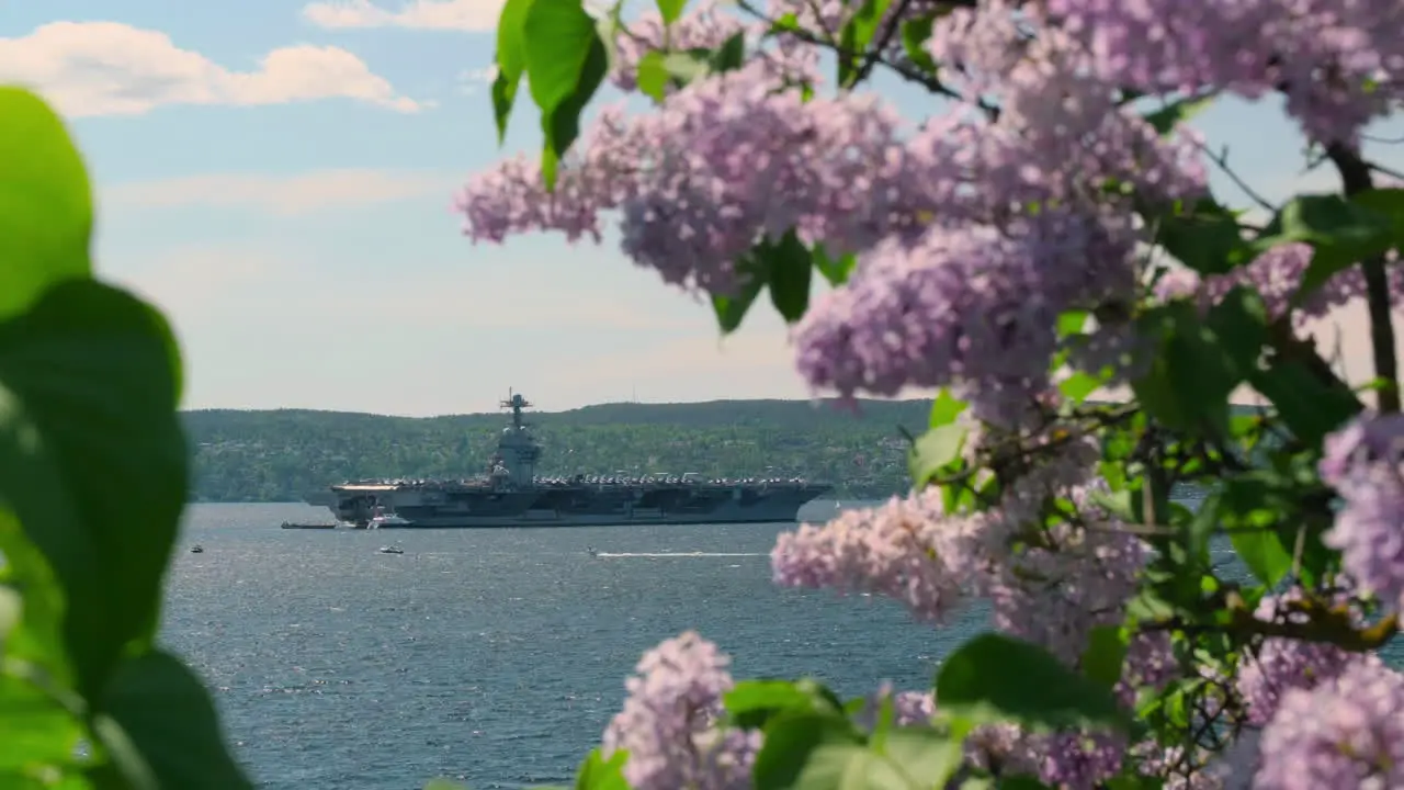 USS Gerard Ford Aircraft Carrier In Oslo Fjord Seen Through Blooming Lilac Bush In Norway