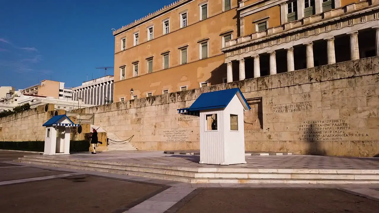 Two Greek presidential guards with traditional military uniform evzone are ending the ceremonial guard change in front of the Hellenic Parliament