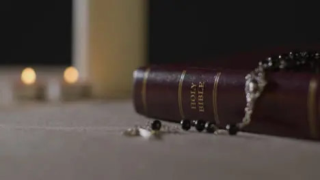 Tracking Shot of Candles Lit around a Bible and a Crucifix