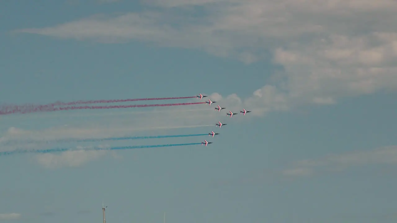 Tracking shot of the Alpha Jets of the Patrouille de France performing with coloured smoke