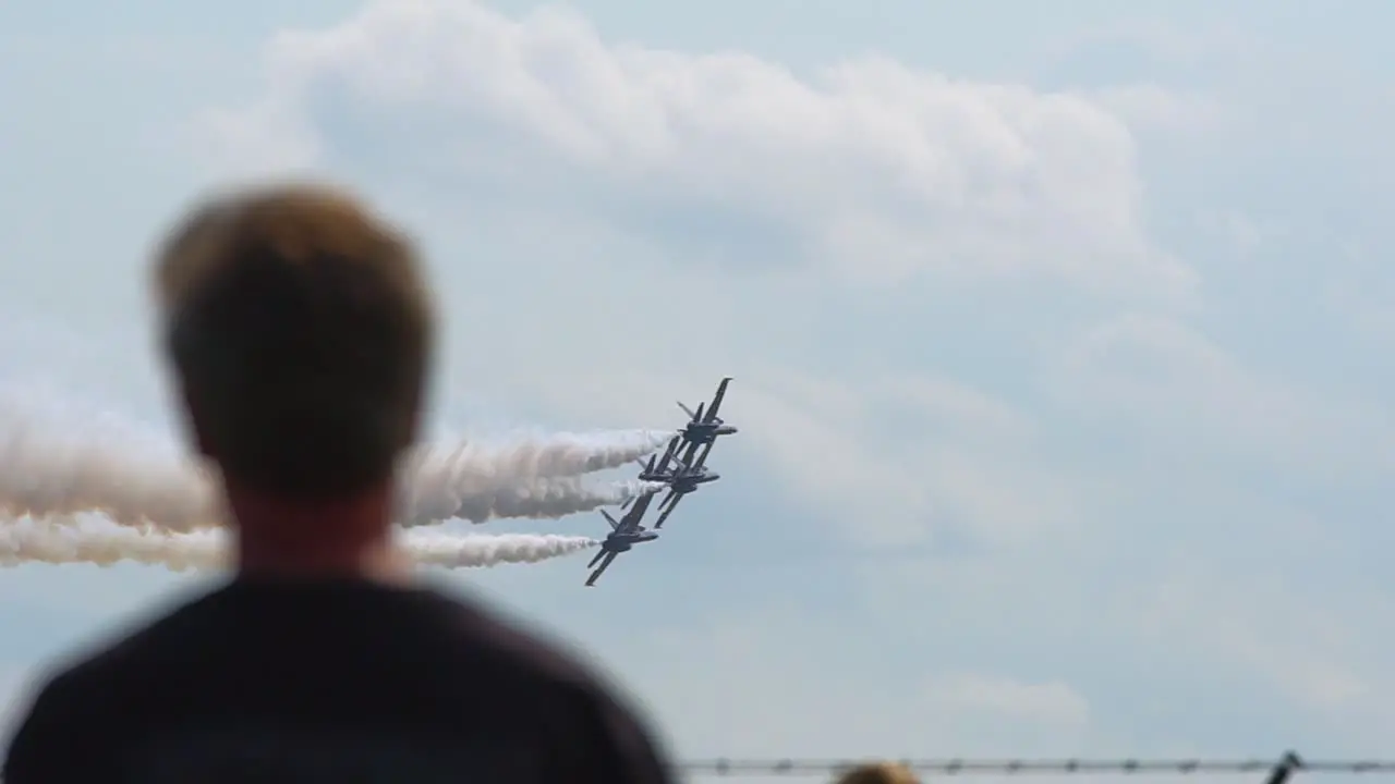 Spectators watch as the Blue Angels fly low near the crowd line while rolling left in a diamond formation at an airshow in VA