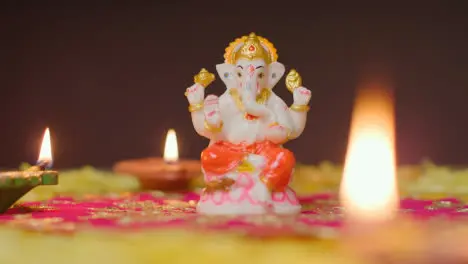 Statue Of Ganesh On Table Decorated With Diya Lamps For Celebrating Festival Of Diwali