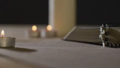 Tracking Shot of Candles Lit around a Bible and Crucifix