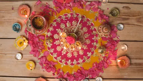 Overhead Shot Of Person Putting Five Wick Lamp On Decorated Table Celebrating Festival Of Diwali