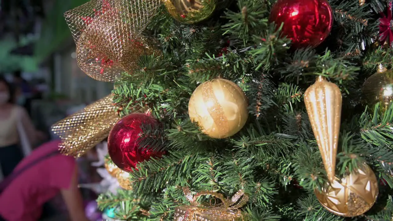 Christmas tree gift red and gold balls ornament decorations are seen hang from a decorated Christmas pine tree