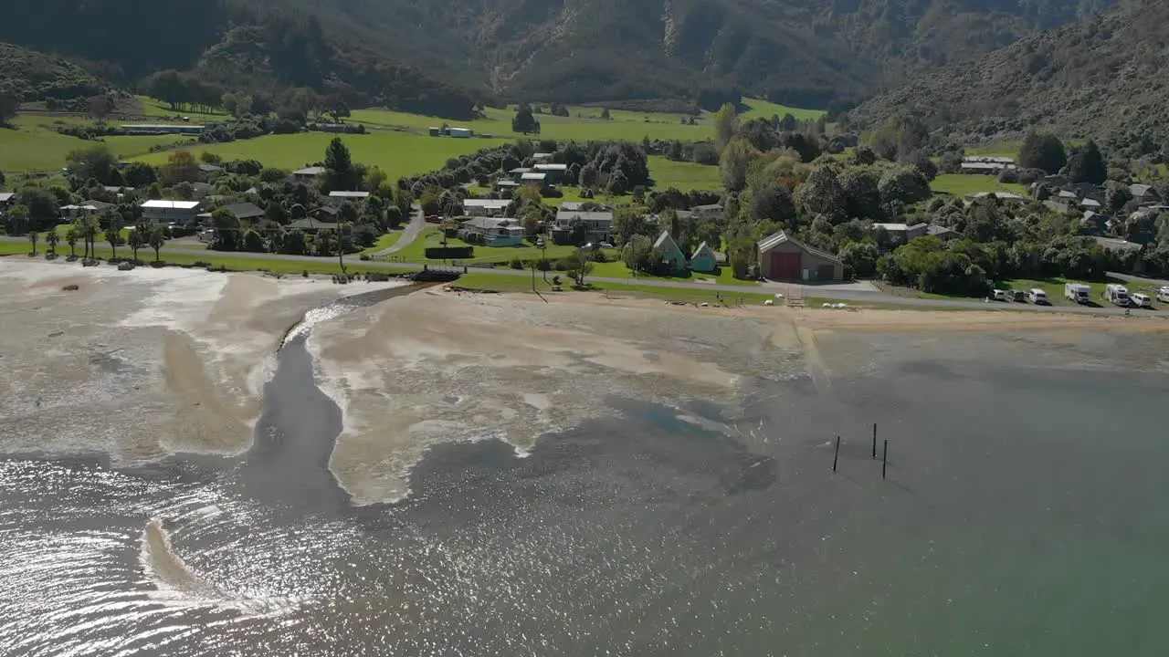 Flying over sea water with Anakiwa town in background Queen Charlotte Sound Marlborough Sounds South Island New Zeland Aerial