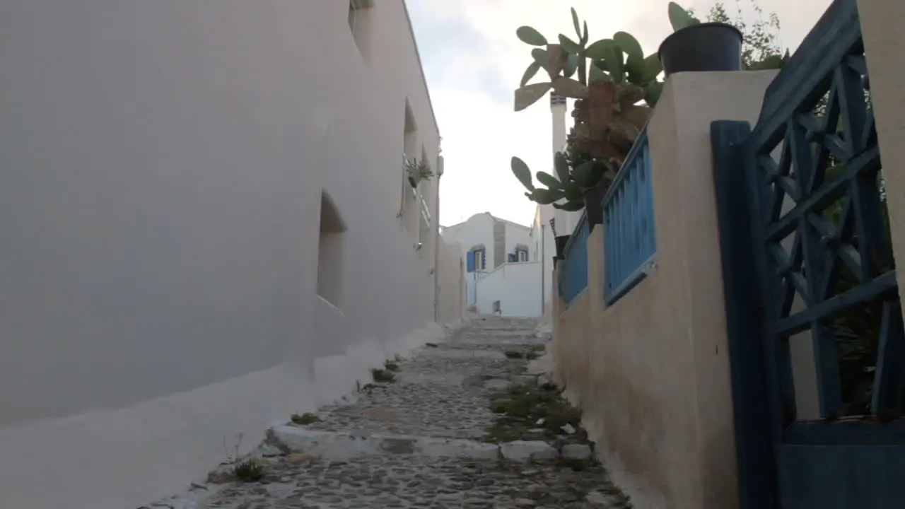 A man is walking up an alley in a Greek cycladic village