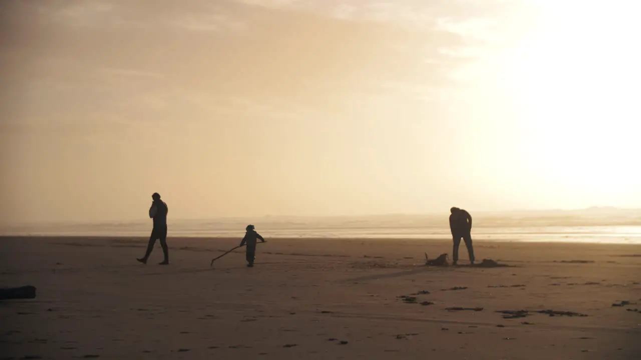 4k slow motion footage of a family playing on the beach with their child while sunset enjoying holiday weekend together