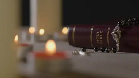 Tracking Shot of Candles Lit around Bible and a Crucifix