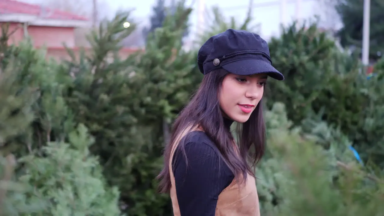 A hispanic woman in the holiday spirit shopping for festive Christmas trees