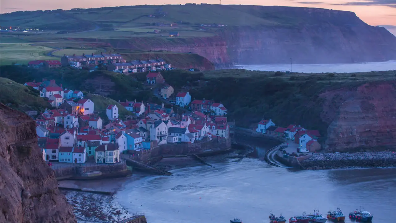 Staithes Harbour and Village Timelapse from headland with mist through to dusk with village lights illuminating atmospheric