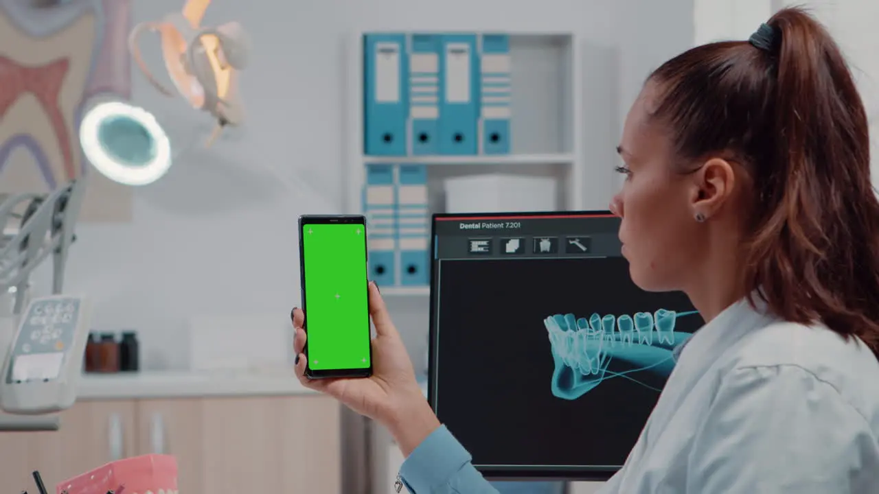 Close up of orthodontist holding smartphone with green screen