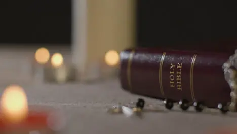 Tracking Shot of Candles Lit around Holy Bible and a Crucifix