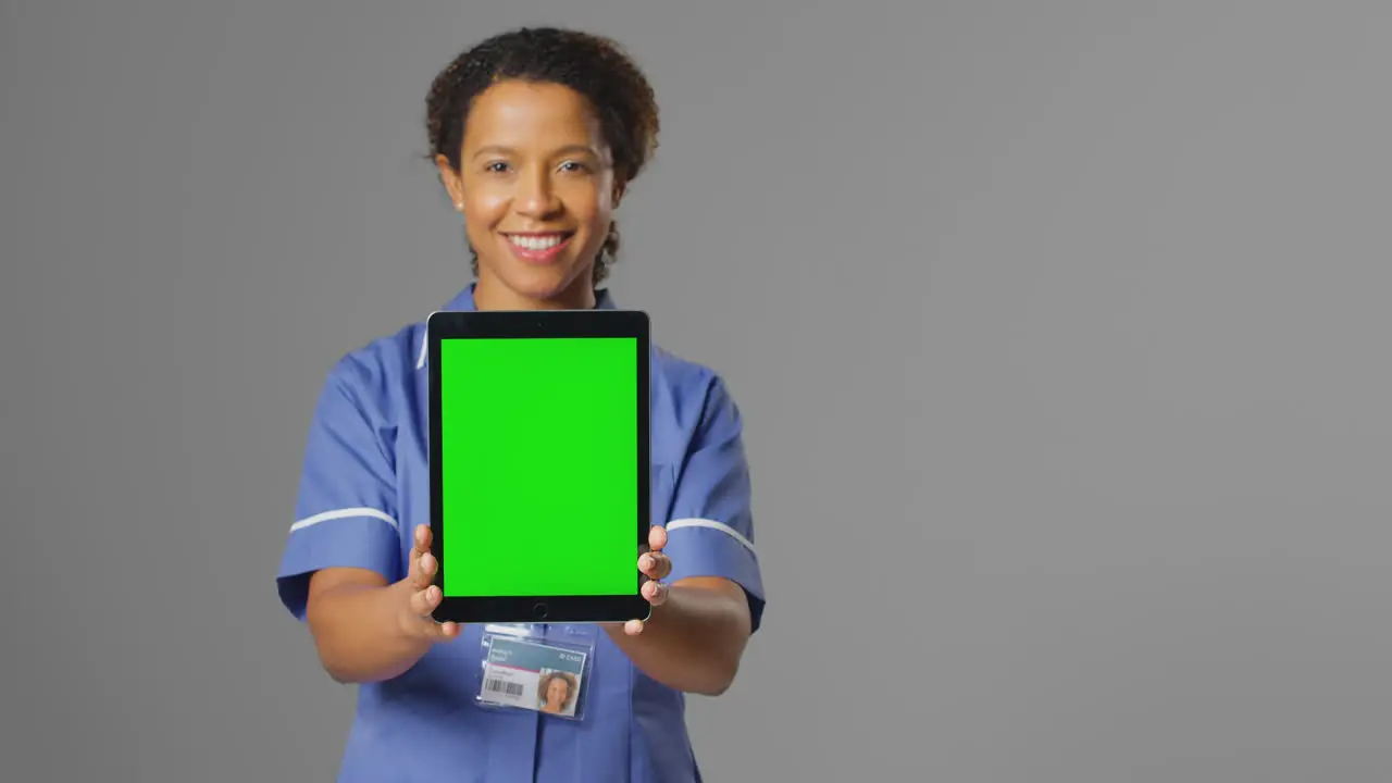 Portrait Of Smiling Nurse Wearing Uniform Holding Digital Tablet With Blank Green Screen