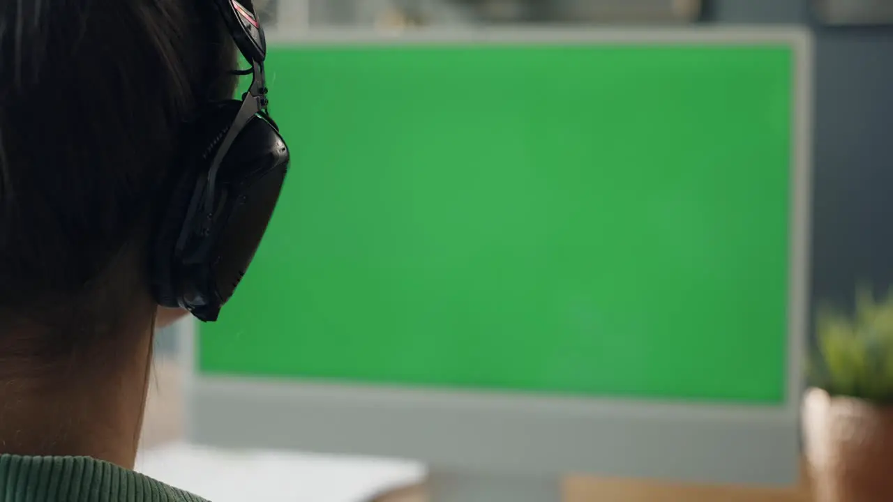 Rear view of woman working on computer with green screen