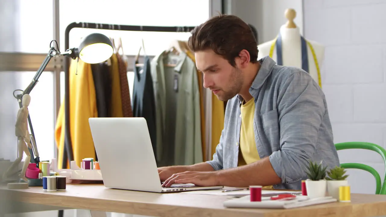 Male Student Or Business Owner Working In Fashion Using Laptop In Studio