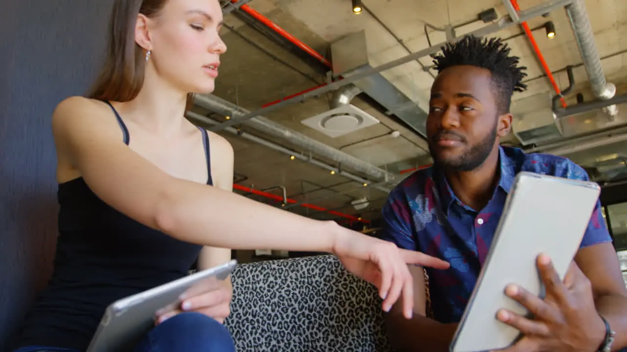 Front view of young cool mixed-race business team planning and sitting on couch of modern office 4k