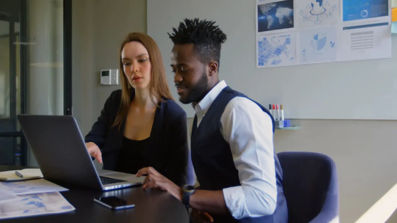 Side view of young cool mixed-race business team planning and sitting at table of modern office 4k