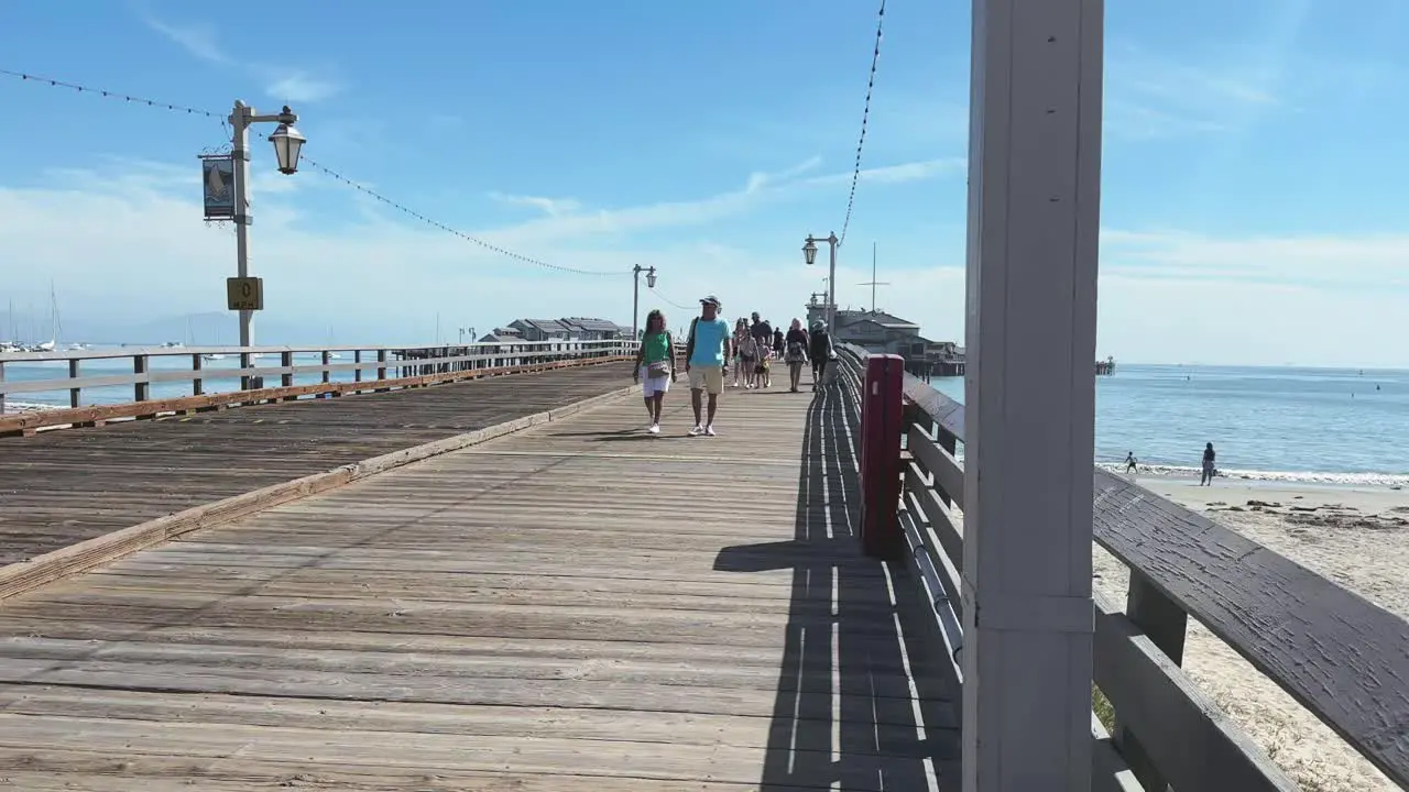 Sunny day and people enjoying the walk on wooden Santa Barbara Pier on Californian coast