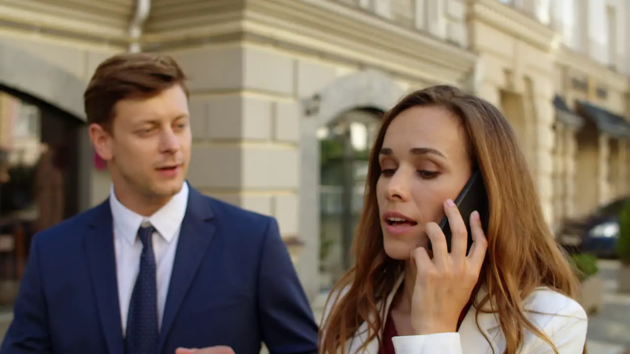 Successful business couple negotiating by mobile phone outdoors