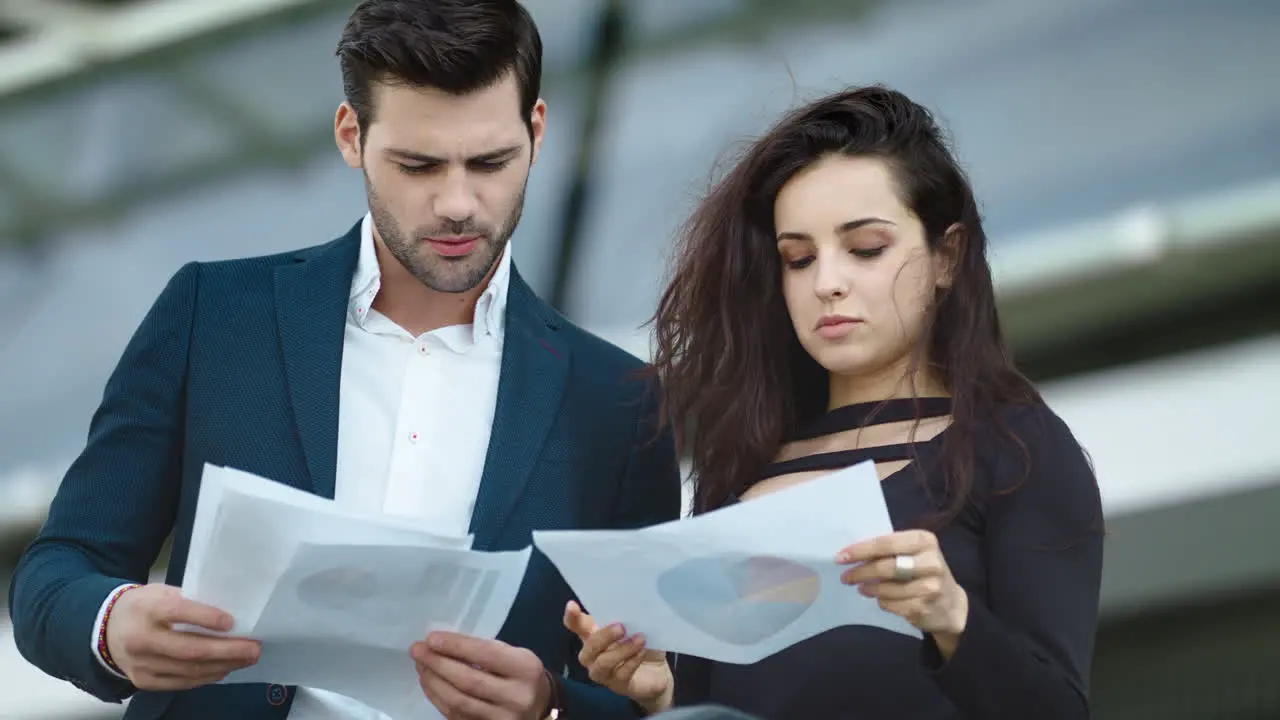 Business couple discussing documents together at street