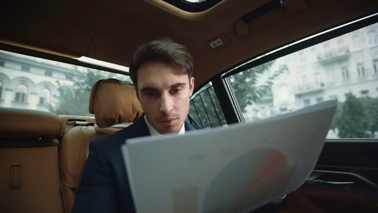 Portrait of focused business man reading documents on back seat of automobile