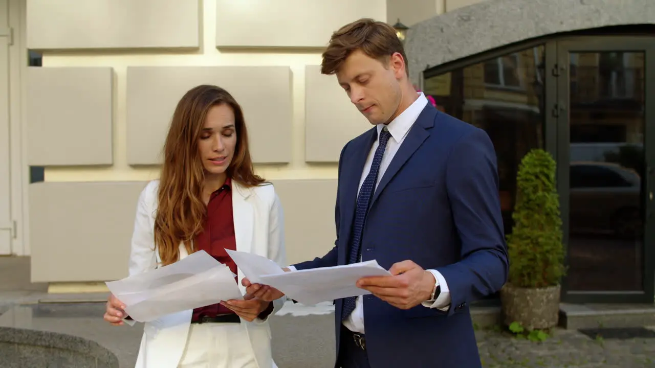 Focused business couple discussing documents outdoors