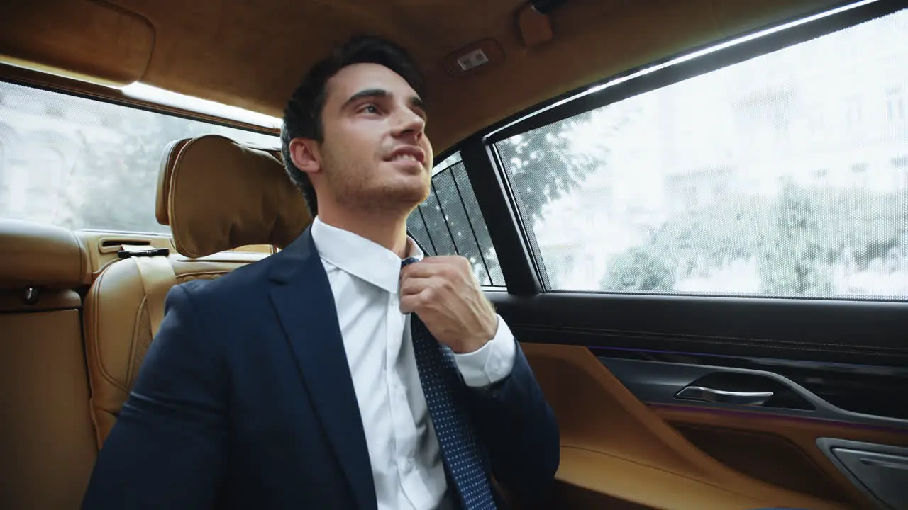 Relaxed male ceo sitting in comfortable car afterwork Business man fixing tie