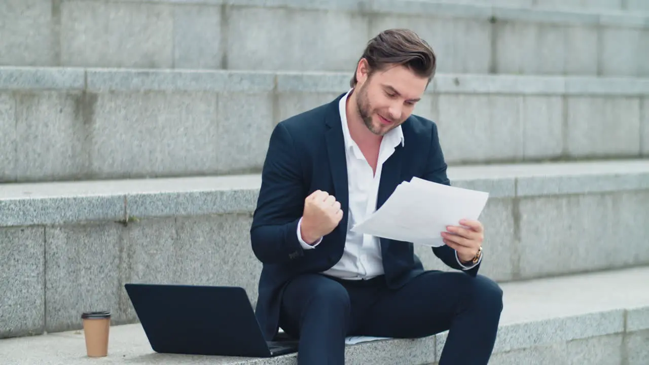 Businessman reading business papers outdoors Male manager celebrating victory