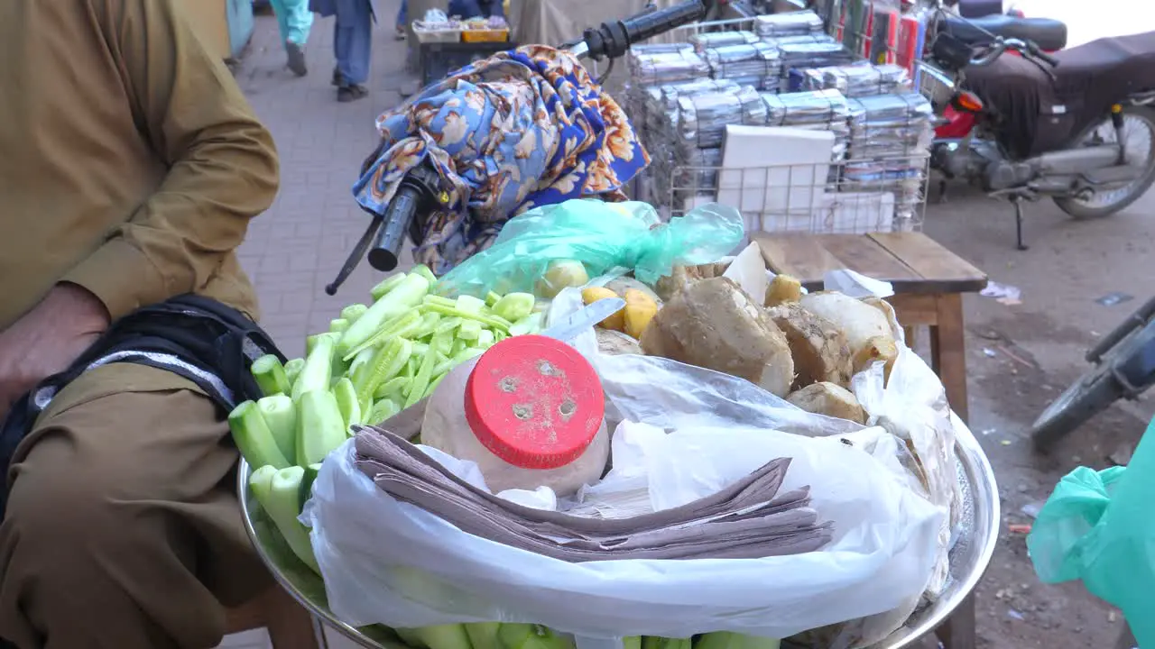 Close up shot of a shopkeeper selling chaats beside a busy Saddar Bazar Street during daytime in Karachi Pakistan