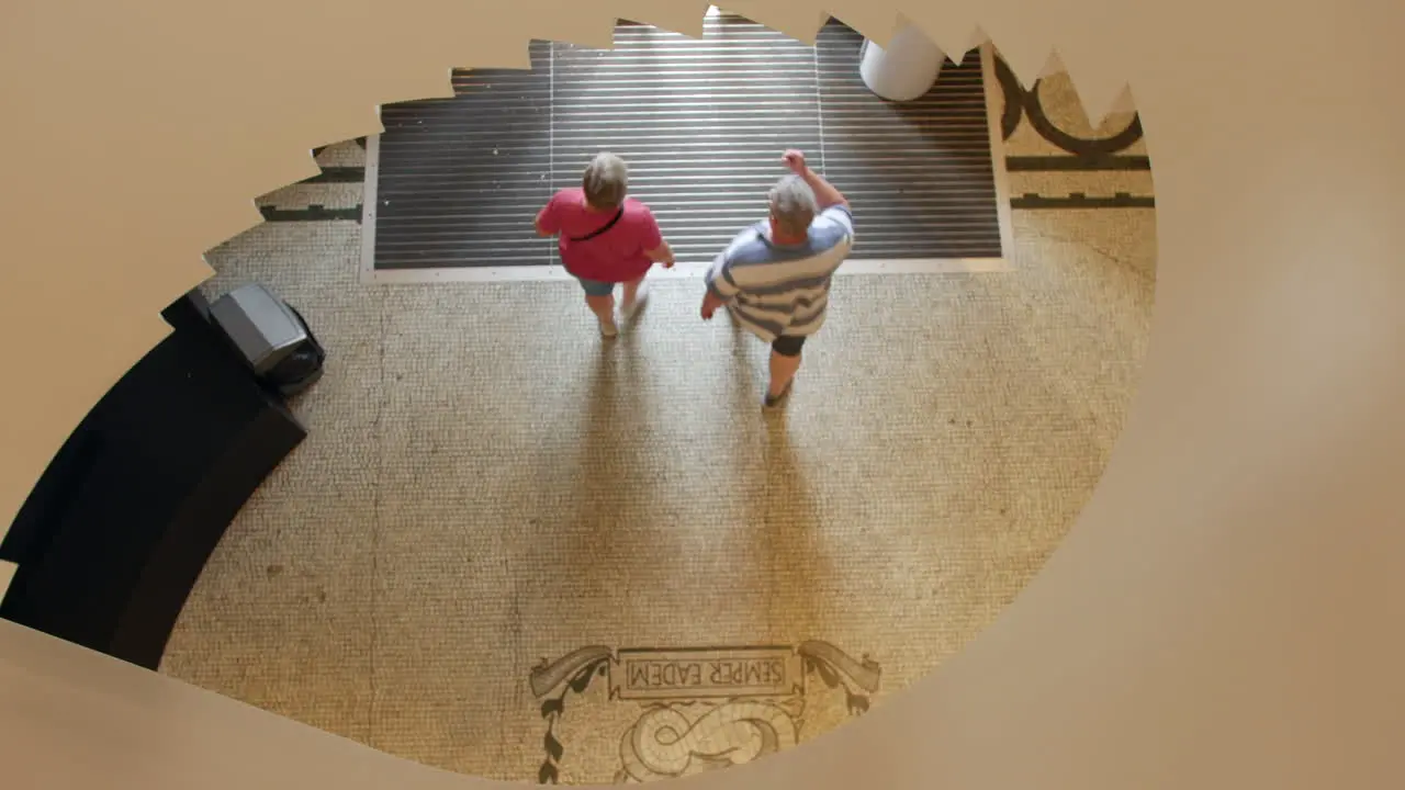 People walking through a museum building entrance hall foyer lobby aerial from a spiral staircase