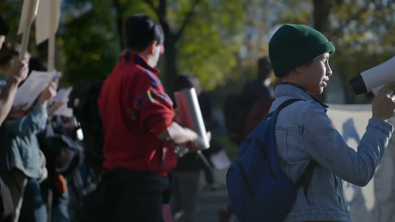 Young girl activist protests on street using megaphone slow motion day