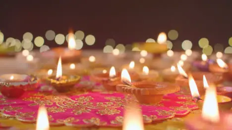 Person Putting Burning Diya Lamp Onto Table Decorated To Celebrate Festival Of Diwali 2