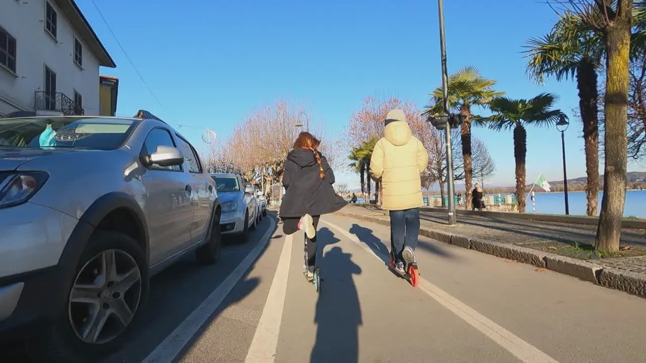 Kids having fun riding scooter along Arona waterfront bicycle lane Italy