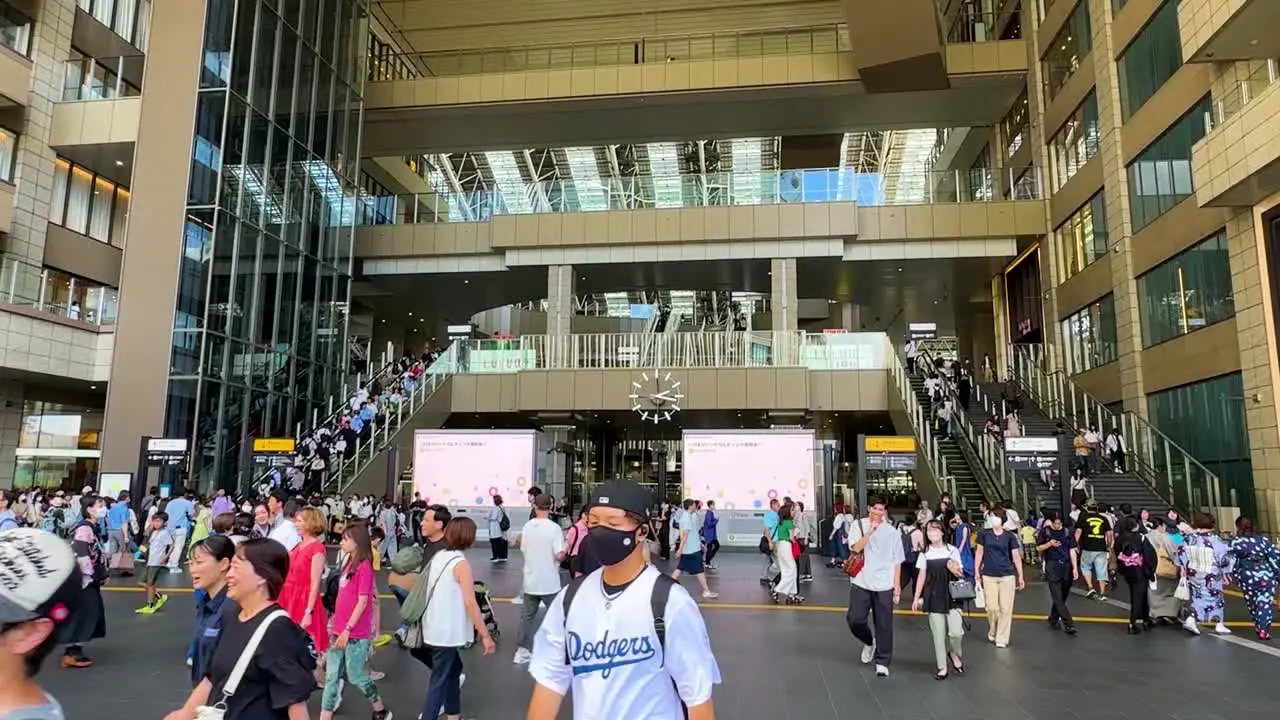 Slow tilting shot showing commuters walking through Osaka Train Station Japan