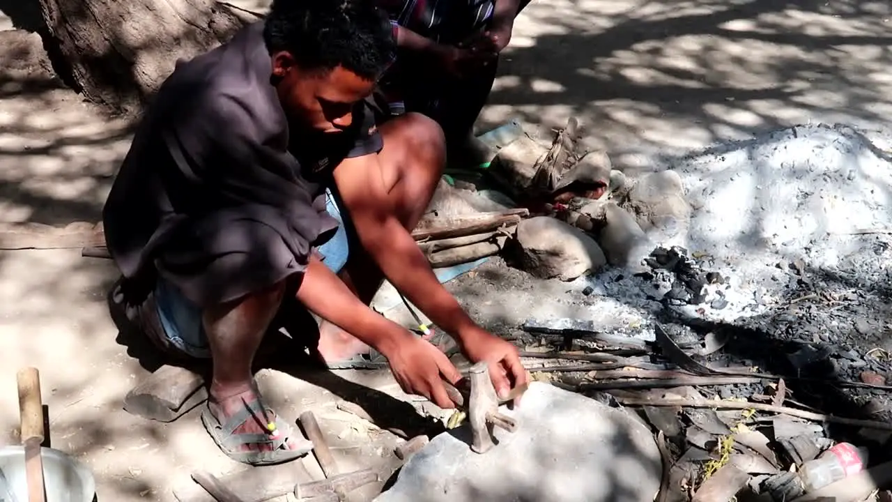 Native African man doing a traditional physically demanding job hammering metal