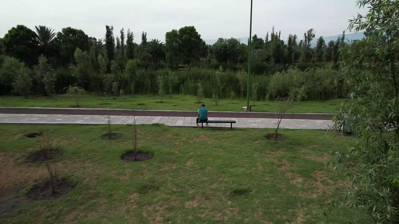 Dolly out with jib up above a lake and natural area with view of a trail and a runner resting in Xochimilco Mexico City