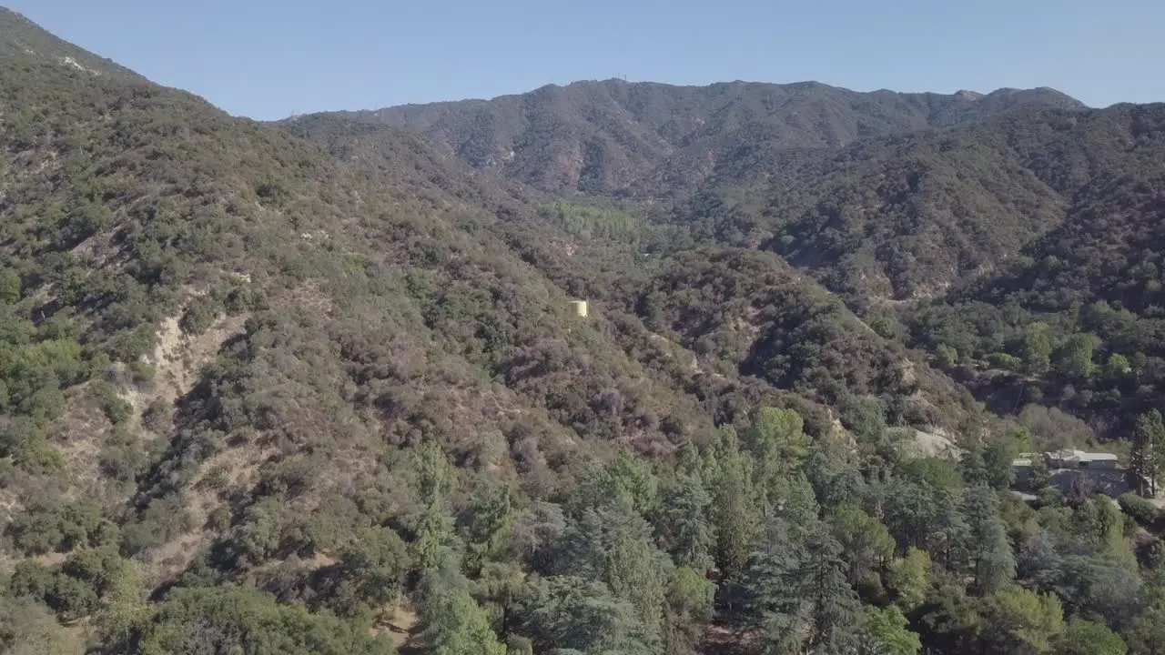 Flying over Los Angeles mountain trees camera panning down