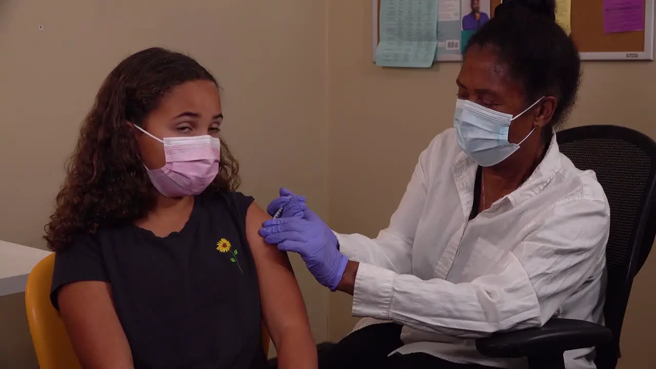 A Nurse Administers The Coronavirus Covid-19 Vaccine Vaccination To A Young Patient