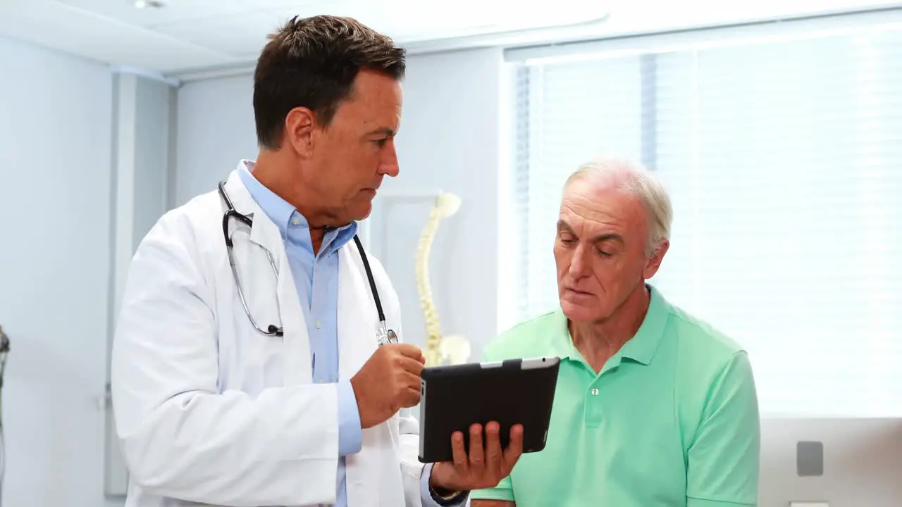 Doctor and senior patient discussing over digital tablet